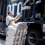 Unos trabajadores de la empresa mexicana Grupo Modelo trasladan paquetes de cervezas para su venta en tiendas de la Ciudad de México (México). EFE/José Pazos