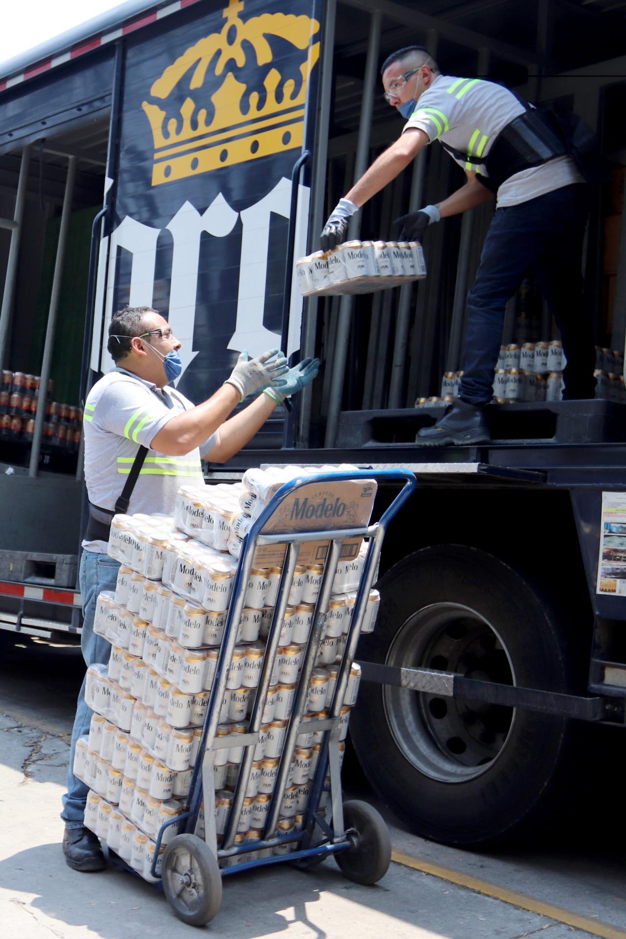 Unos trabajadores de la empresa mexicana Grupo Modelo trasladan paquetes de cervezas para su venta en tiendas de la Ciudad de México (México). EFE/José Pazos