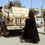 Fotografía de archivo fechada el 8 de septiembre de 2004 que muestra a una mujer iraquí que se cruza con soldados estadounidenses que patrullan las calles de Bagdad (Irak). EFE/ Mohammed Messara