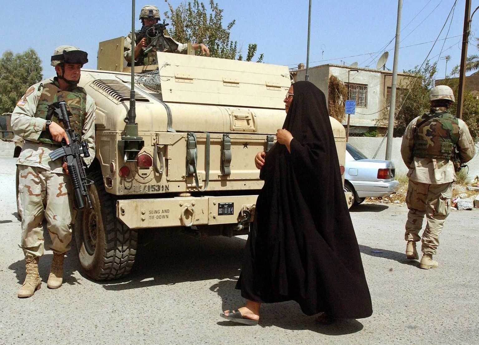 Fotografía de archivo fechada el 8 de septiembre de 2004 que muestra a una mujer iraquí que se cruza con soldados estadounidenses que patrullan las calles de Bagdad (Irak). EFE/ Mohammed Messara