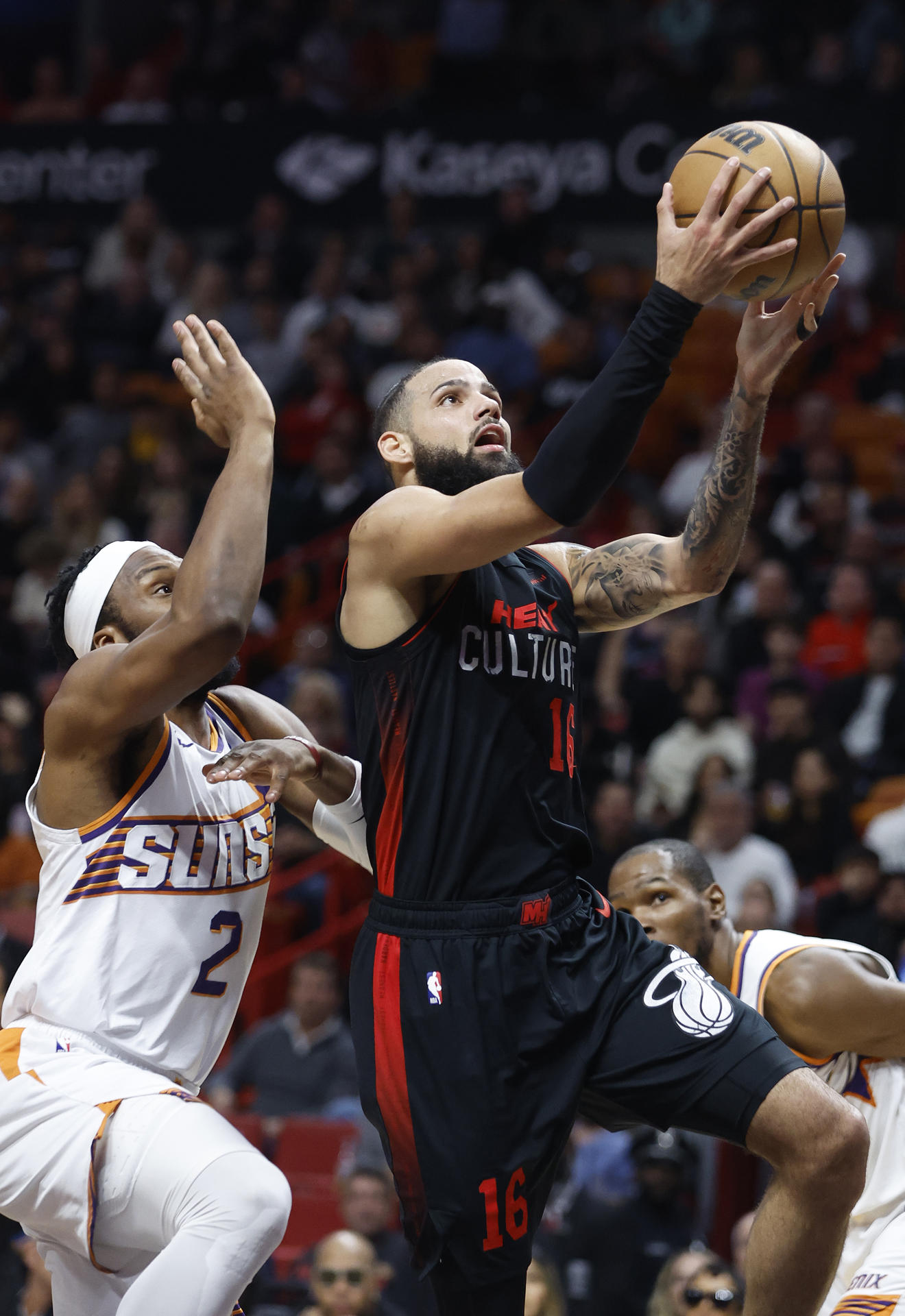 El delantero del Miami Heat, Caleb Martin (derecha), dispara alrededor del delantero de los Phoenix Suns, Josh Okogie (izq.) hoy, durante la primera mitad del partido de baloncesto de la NBA entre los Miami Heat y los Phoenix Suns en el Kaseya Center de Miami, Florida (EE. UU). EFE/ Rhona Wise
