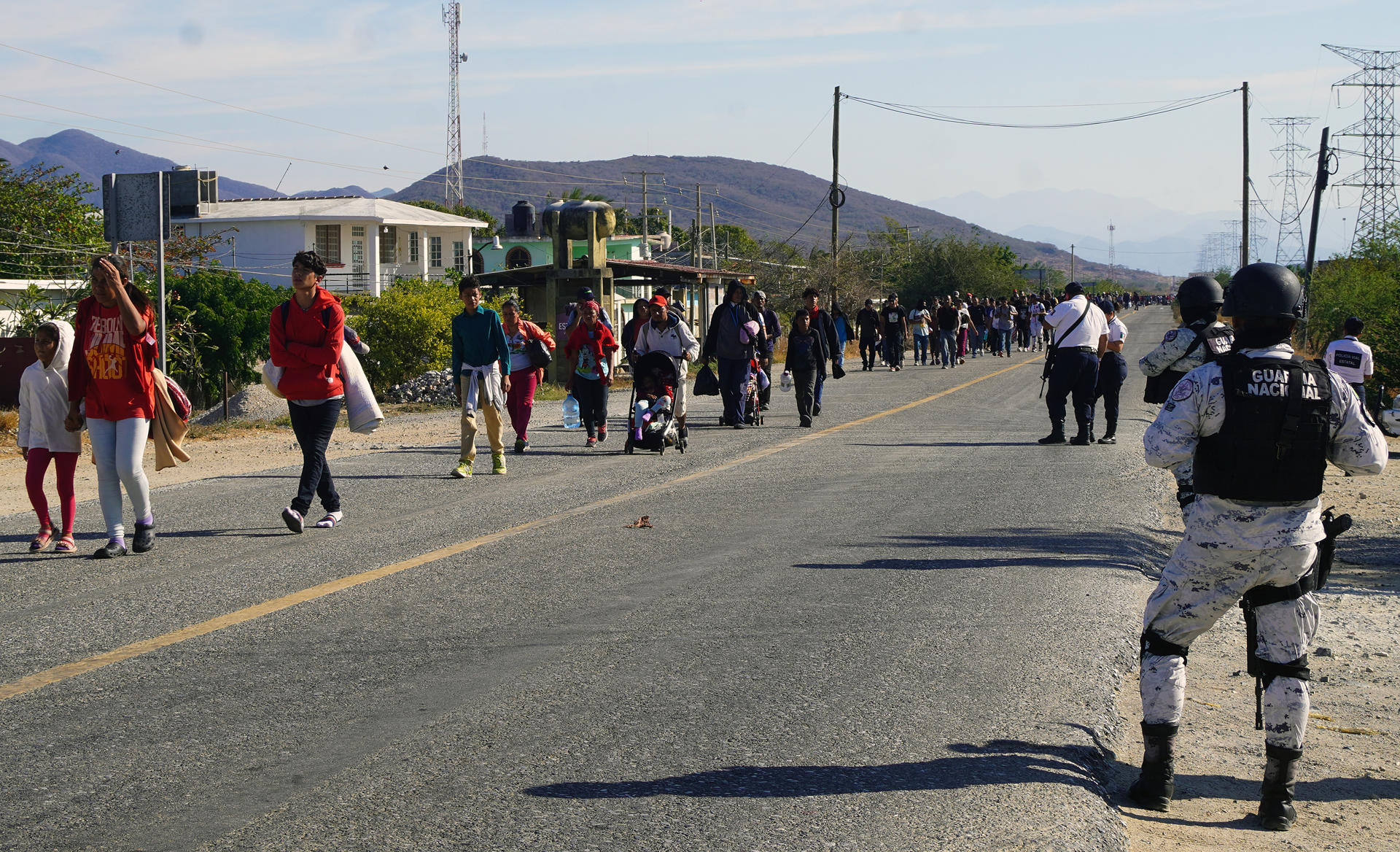 Personal de la Guardia Nacional (GN) custodian a migrantes que caminan durante una caravana que se dirige a la frontera con Estados Unidos hoy, en el municipio de Juchitán en el estado de Oaxaca (México). EFE/Jesús Méndez
