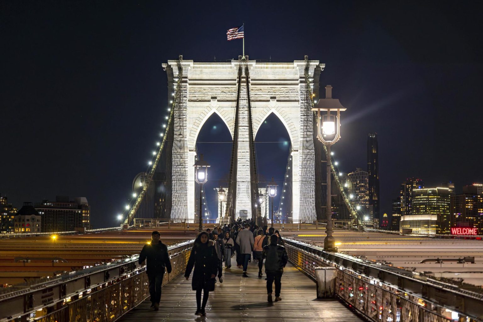 Fotografía cedida por el Departamento de Transportes de Nueva York (NYC DOT) que muestra transeúntes mientras caminan por el puente de Brooklyn después de la iluminación de sus arcos el 11 de enero de 2024, en Nueva York (EE.UU.). EFE/ NYC DOT SÓLO USO EDITORIAL/SÓLO DISPONIBLE PARA ILUSTRAR LA NOTICIA QUE ACOMPAÑA (CRÉDITO OBLIGATORIO)