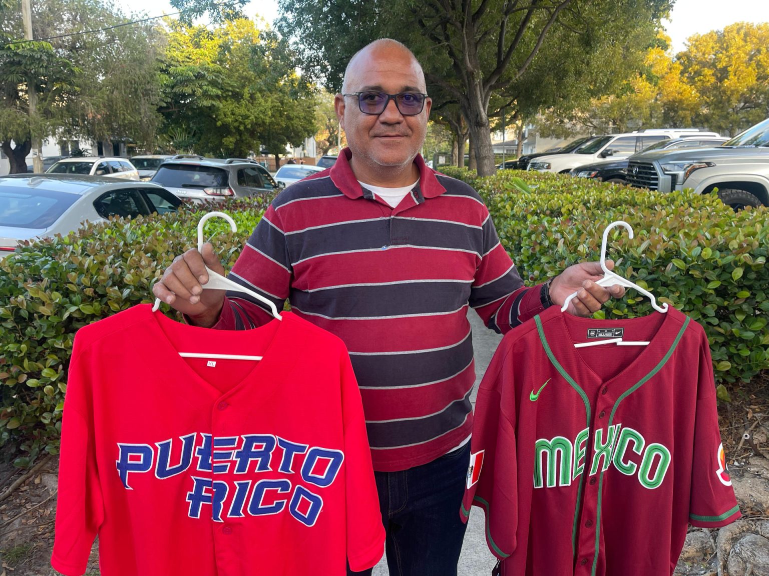 El vendedor José Godoy muestra unas camisetas de béisbol de Puerto Rico y México hoy, en Miami (Estados Unidos). EFE/Antoni Belchi