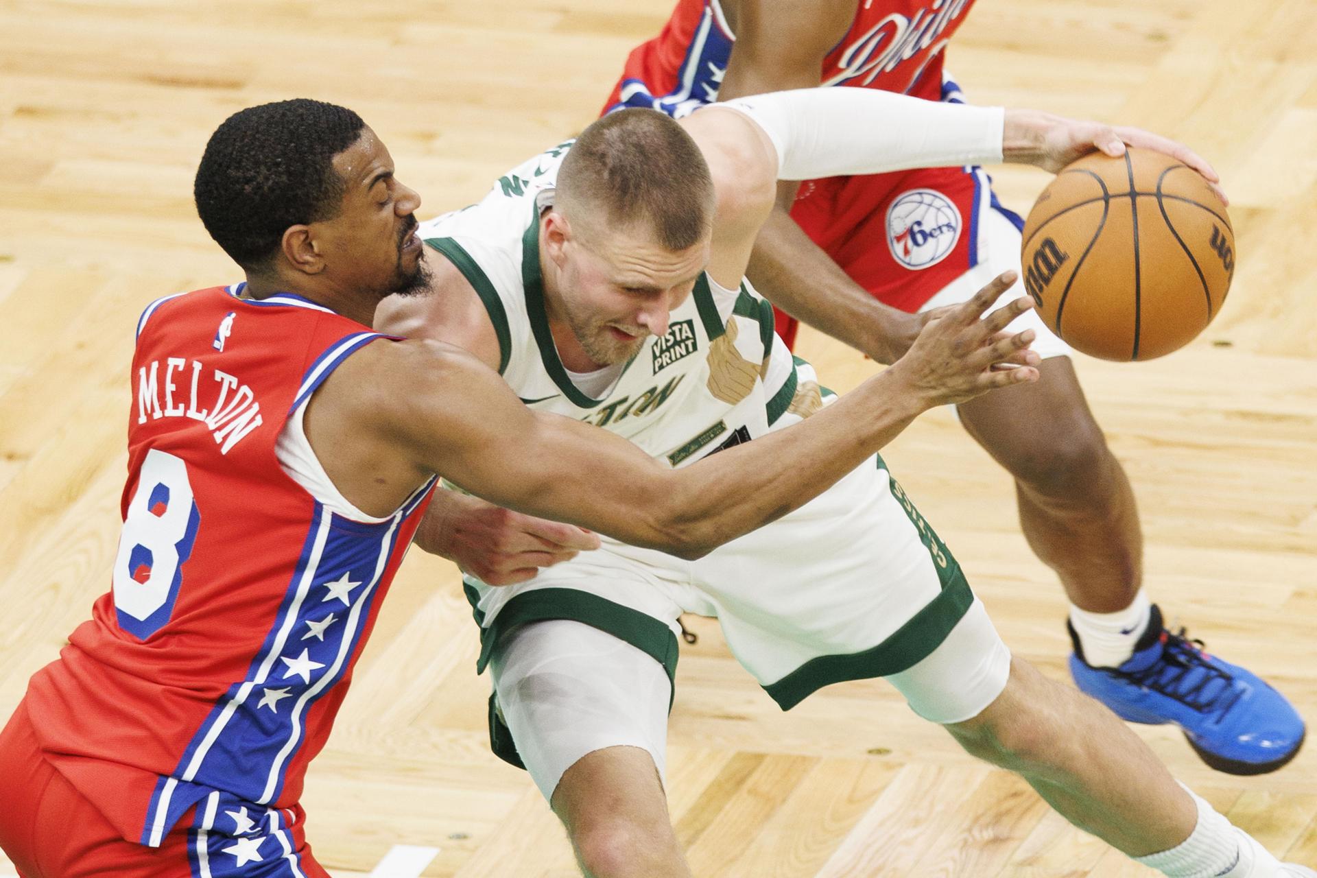 Kristaps Porzingis (i),ala pívot de los Celtics de Boston, fue registrado este martes, 27 de febrero, al intentar superar la marca de De'Anthony Melton, de los 76ers de Filadelfia, durante un partido de la NBA, en Boston (Massachusetts, EE.UU.). EFE/CJ Gunther
