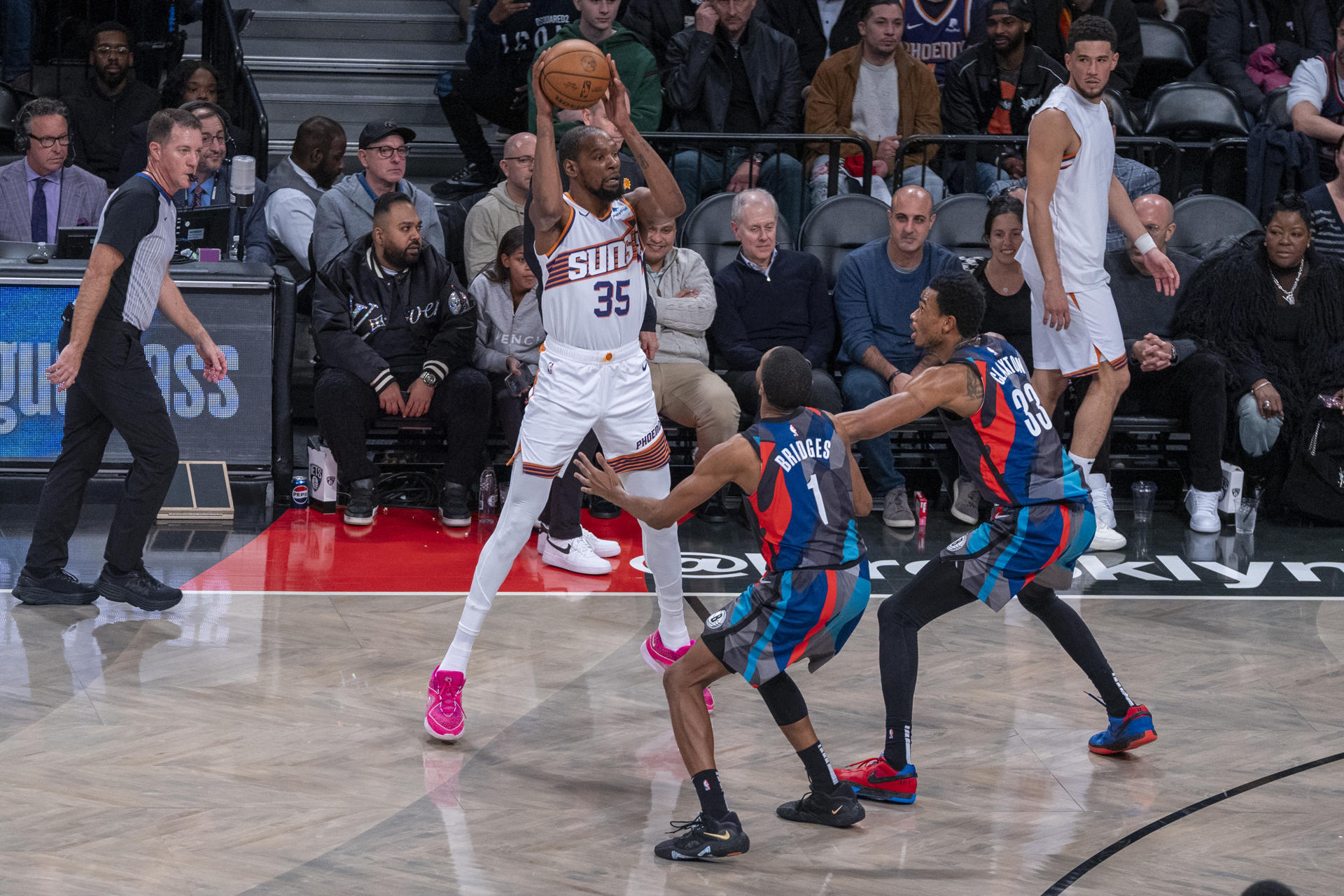 Kevin Durant (i) de los Suns busca a quién pasar el balón bajo la marca de los jugadores de los Nets Mikal Bridges (c) y Nicolas Claxton (d) hoy, durante un partido de baloncesto de la NBA entre Brooklyn Nets y Phoenix Suns, disputado en el pabellón deportivo multiusos Barclays Center en el barrio de Prospect Heights, Brooklyn, Nueva York (EE.UU.). EFE/ Ángel Colmenares
