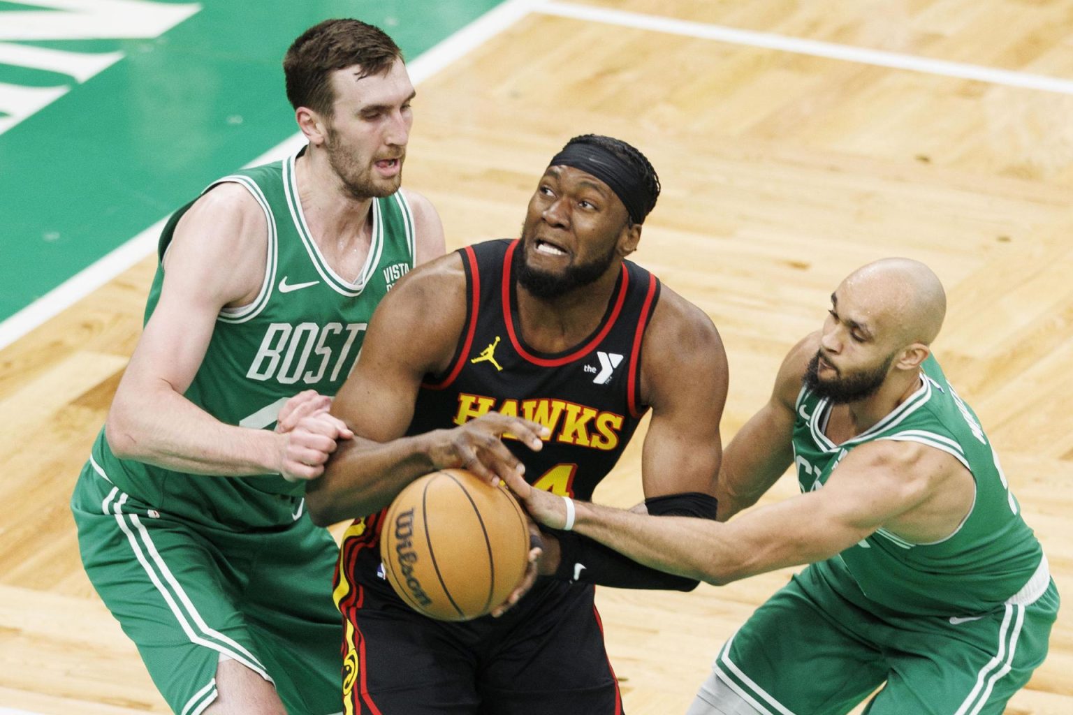 El guardia de los Boston Celtics, Derrick White (d), aleja el balón del delantero de los Atlanta Hawks, Bruno Fernando (c), mientras el centro de los Boston Celtics, Luke Kornet (i), defiende. EFE/EPA/CJ GUNTHER