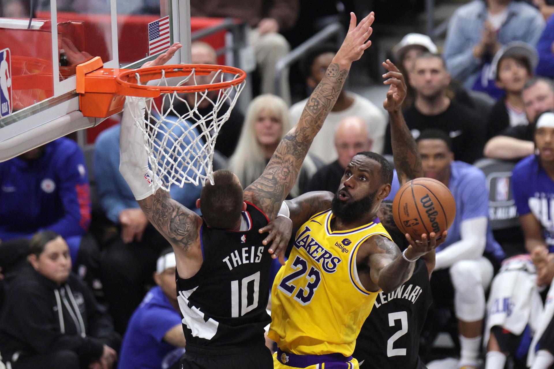 El jugador de los Angeles Lakers LeBron James (d) entra a canasta con la defensa del jugador de los Angeles Clippers Daniel Theis (i) durante la segunda mitad del partido de baloncesto de la NBA entre los Angeles Lakers y Los Angeles Clippers en Los Ángeles, California, EE. UU. EFE/EPA/ALLISON DINNER
