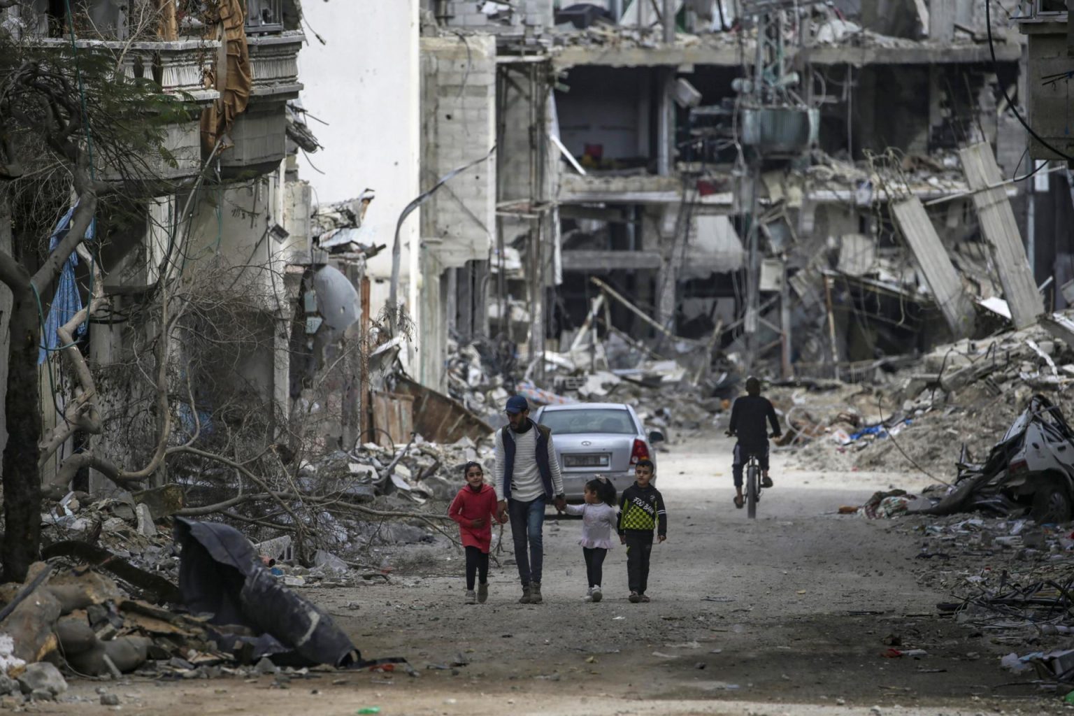 Una familia palestina camina entre la destrucción en el campo de refugiados de Al Bureije (Gaza) este martes. . EFE/MOHAMMED SABER