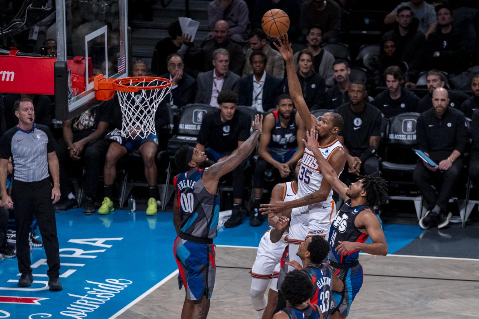 Kevin Durant (c) salta a la canasta sobre la marca de Royce O'Neale (i) de los Nets hoy, durante un partido de baloncesto de la NBA entre Brooklyn Nets y Phoenix Suns, disputado en el pabellón deportivo multiusos Barclays Center en el barrio de Prospect Heights, Brooklyn, Nueva York (EE.UU.). EFE/ Ángel Colmenares