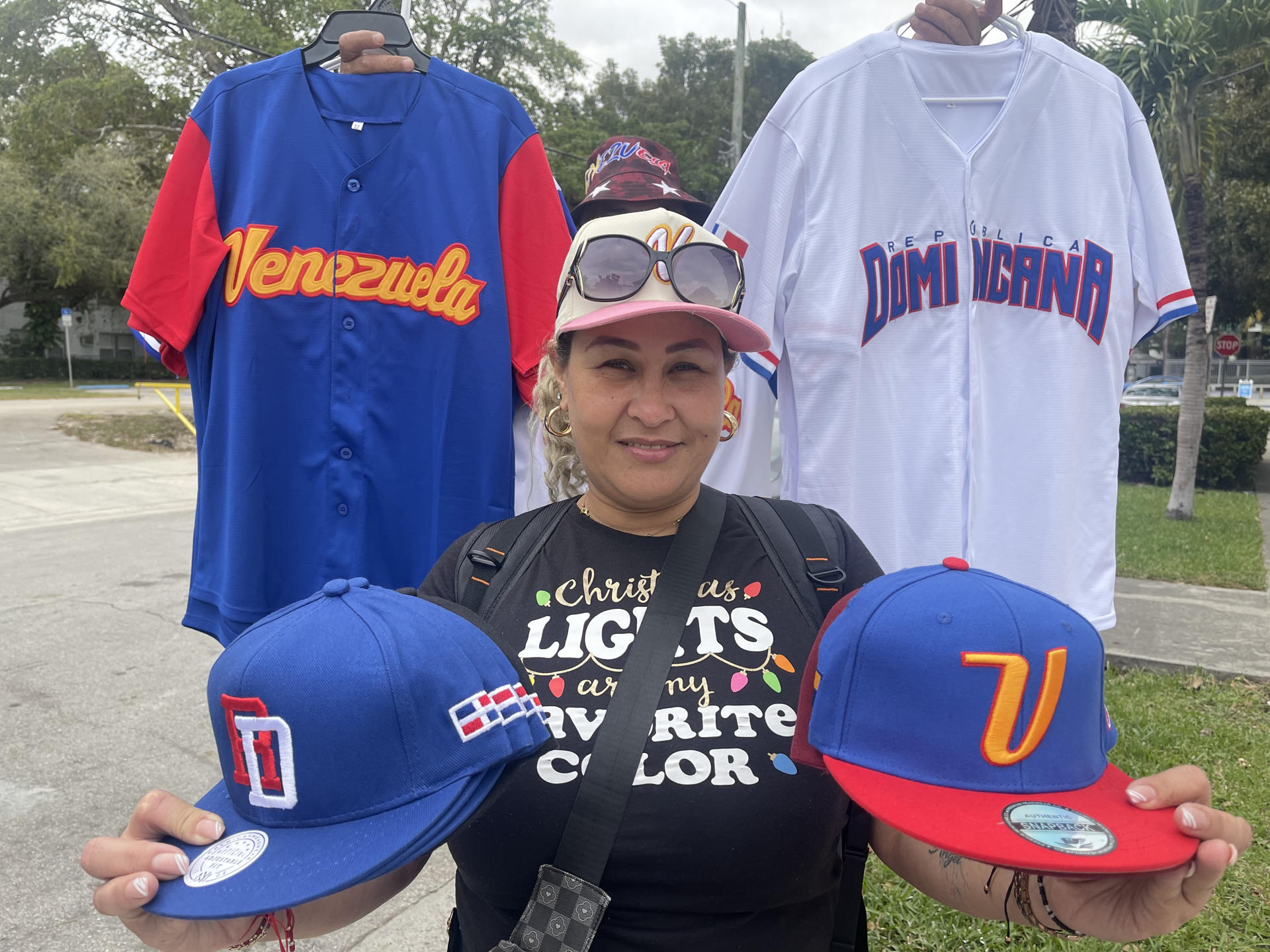 La vendedora Ingrid Pelayo posa para EFE con gorras alusivas a República Dominicana y Venezuela en Miami (Estados Unidos). EFE/ Antoni Belchi
