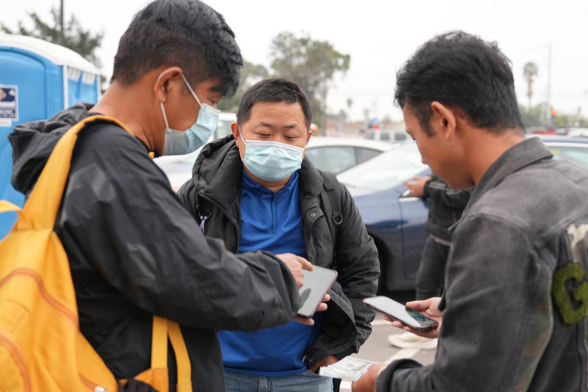 Un grupo de migrantes chinos liberados por la Patrulla Fronteriza intercambian números teléfonicos este lunes, en San Diego, California (EE.UU.). EFE/ Manuel Ocaño
