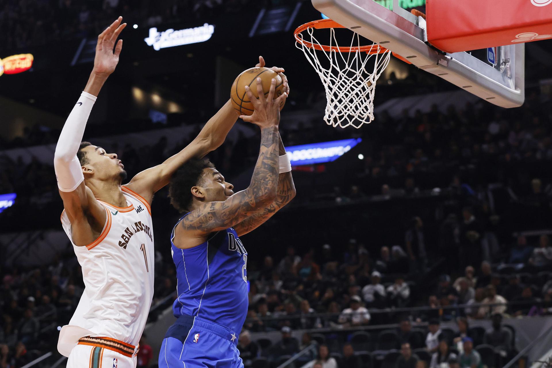 El francés Victor Wembanyama, pívot de los Spurs de San Antonio, fue registrado este martes, 19 de marzo, al taparle un balón a Daniel Gafford (d), de los Mavericks de Dallas, durante un partido de la NBA, en San Antonio (Texas, EE.UU.). EFE/Adam Davis
