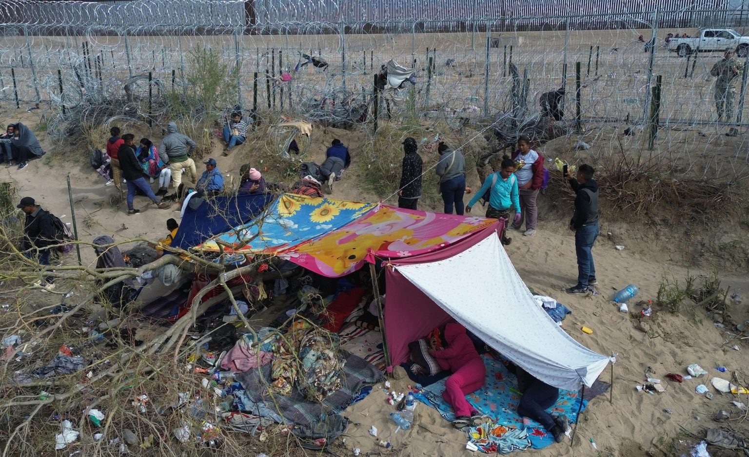 Migrantes permanecen en las inmediaciones del Río Bravo, junto al alambrado que divide a México con Estados Unidos, este miércoles, en Ciudad Juárez (México). EFE/ Luis Torres