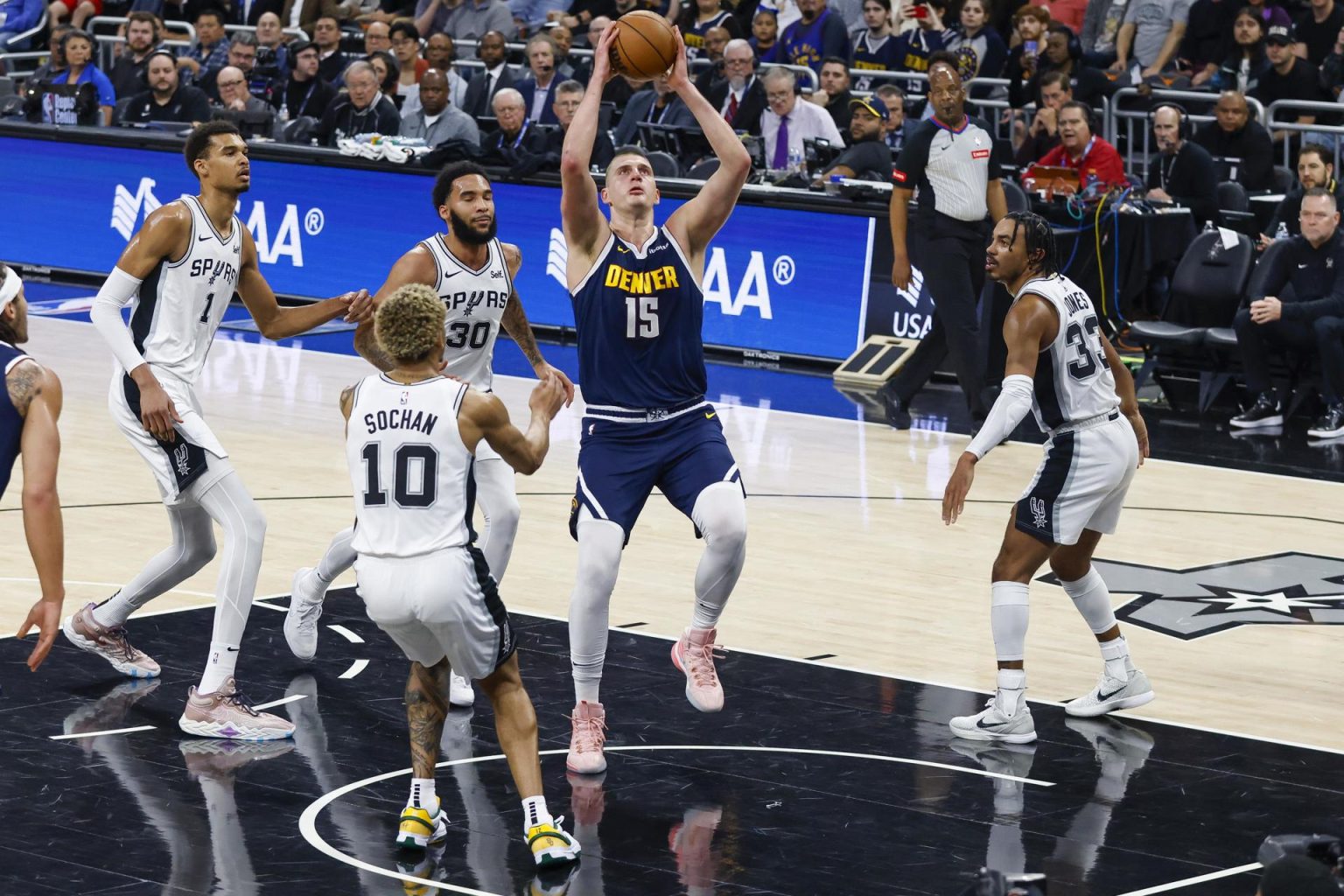 El serbio Nikola Jokic (c), pívot estrella de los Nuggets de Denver, fue registrado este viernes, 15 de marzo, al atacar el aro que defienden los Spurs de San Antonio, durante un partido de la NBA, en Austin (Texas, EE.UU.). EFE/Adam Davis