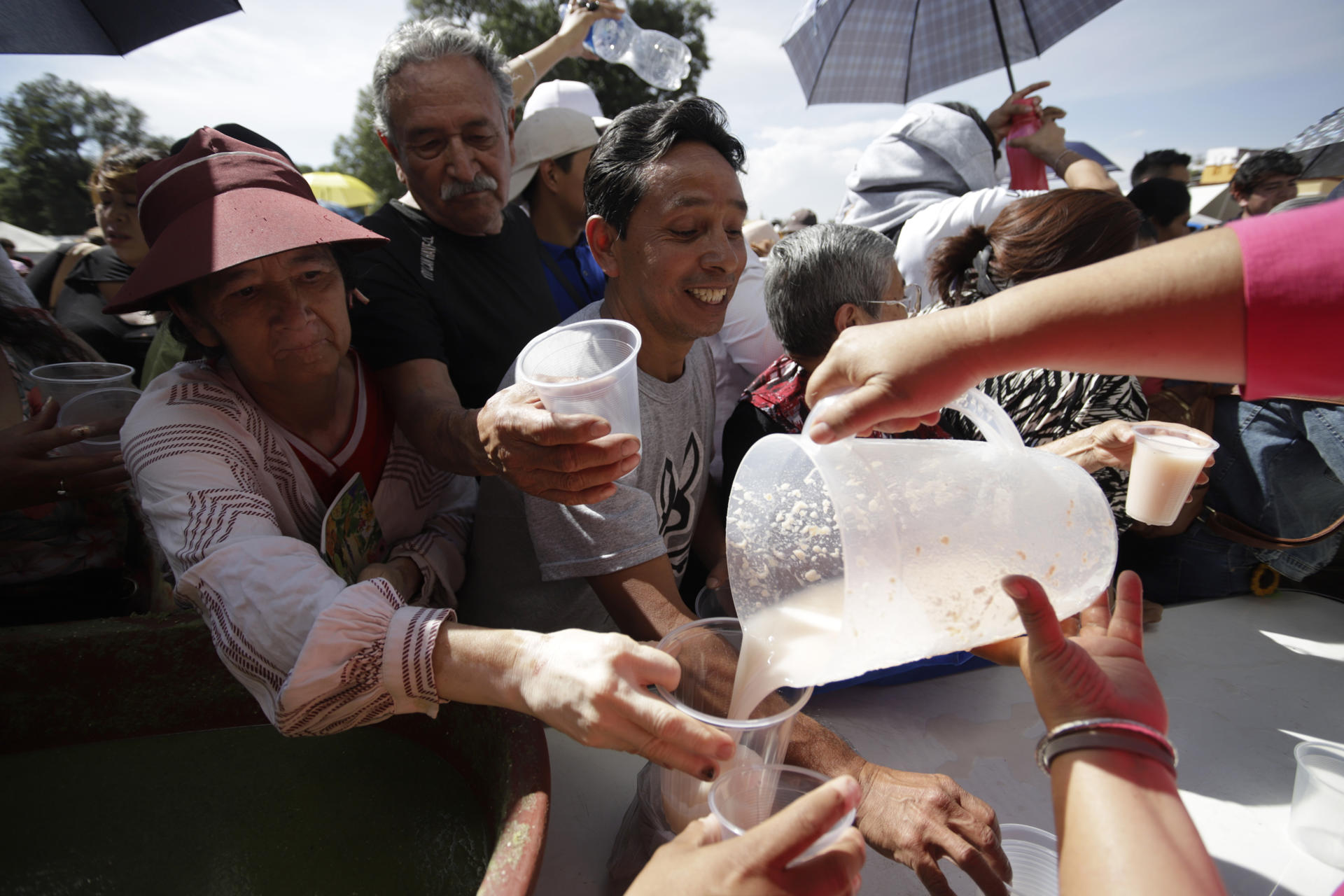 Una mujer reparte 'pulque' (bebida prehispánica) a habitantes de San Pedro Cholula (México). EFE/ Hilda Ríos
