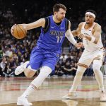 El esloveno Luka Doncic (c), escolta estrella de los Mavericks de Dallas, fue registrado este martes, 19 de marzo, al intentar superar la marca de Keldon Johnson (d), de los Spurs de San Antonio, durante un partido de la NBA, en San Antonio (Texas, EE.UU.). EFE/Adam Davis