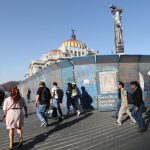 Personas caminan junto a unas vallas metálicas que rodean el Palacio Nacional de Bellas Artes, este viernes, en la Ciudad de México (México). EFE/Mario Guzmán