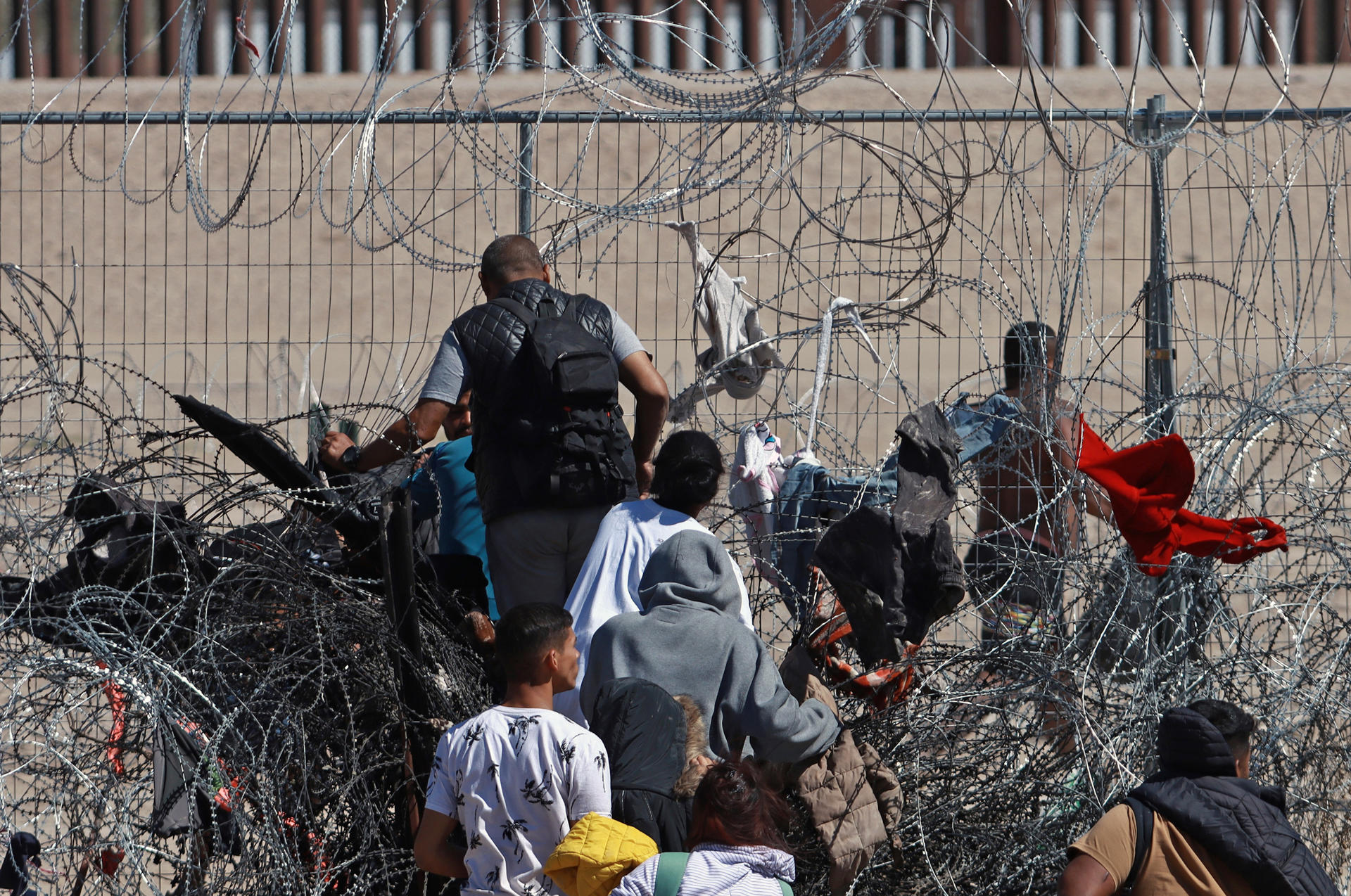 Migrantes cruzan una cerca de alambres en la frontera que divide a México de los Estados Unidos, este jueves en Ciudad Juárez (México). EFE/Luis Torres
