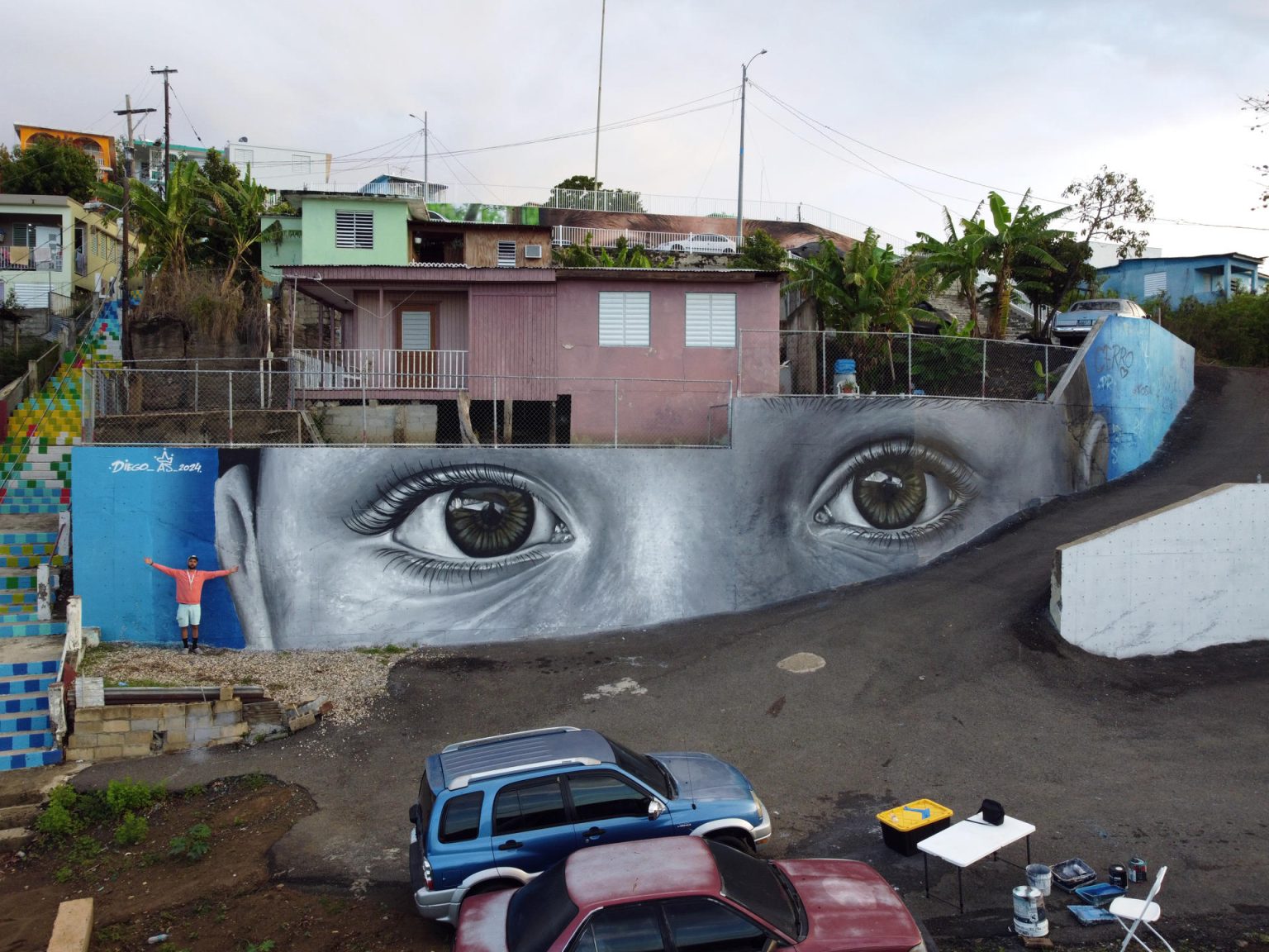 Fotografía cedida por la organización 'Arte para Unir' donde aparece el artista español Diego As (i) mientras posa junto a su mural que forma parte del proyecto 'Miradas del barrio', realizado en el barrio de El Cerro, en Yauco (Puerto Rico). EFE/Arte para Unir /SOLO USO EDITORIAL /NO VENTAS /SOLO DISPONIBLE PARA ILUSTRAR LA NOTICIA QUE ACOMPAÑA /CRÉDITO OBLIGATORIO