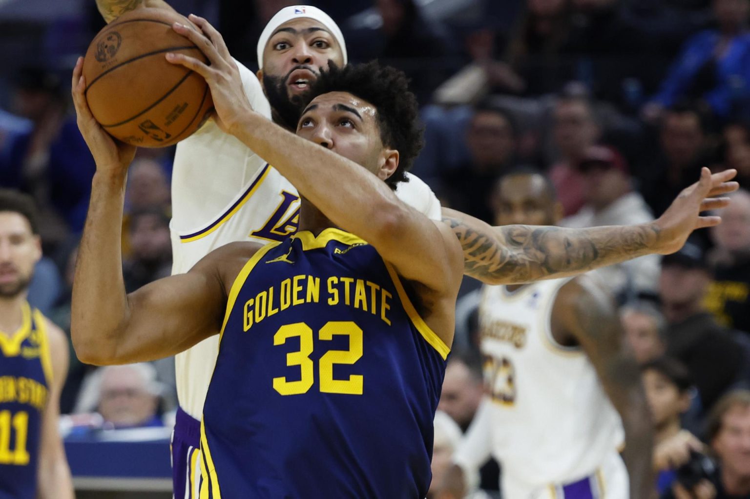 Fotografía de archivo, tomada el pasado 24 de enero, en la que se registró a Anthony Davis (i), alero estrella de los Lakers de Los Ángeles, al intentar gardear un balón a Trayce Jackson-Davis (c), de los Warriors de Golden State, durante un partido de la NBA. En un nuevo enfrentamiento entre este par de equipos californianos, Davis salió lesionado por un golpe en un ojo. EFE/John G. Mabanglo