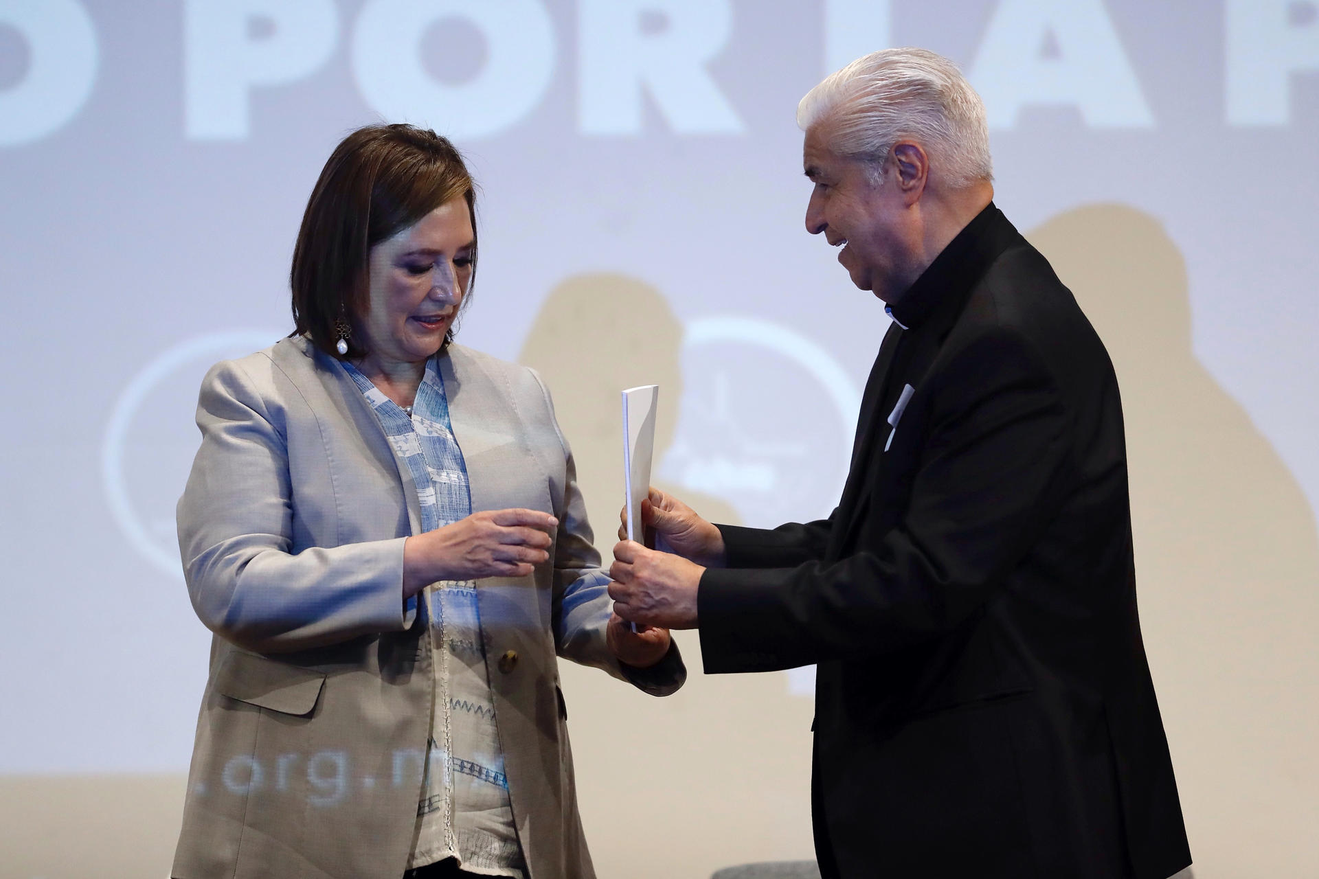 El presidente del Episcopado Mexicano, Rogelio Cabrera (d), le entrega el compromiso por la paz a la candidata presidencial de la coalición opositora 'Fuerza y Corazón por México', Xóchitl Gálvez (i), este lunes, en la Ciudad de México (México). EFE/ Sáshenka Gutiérrez
