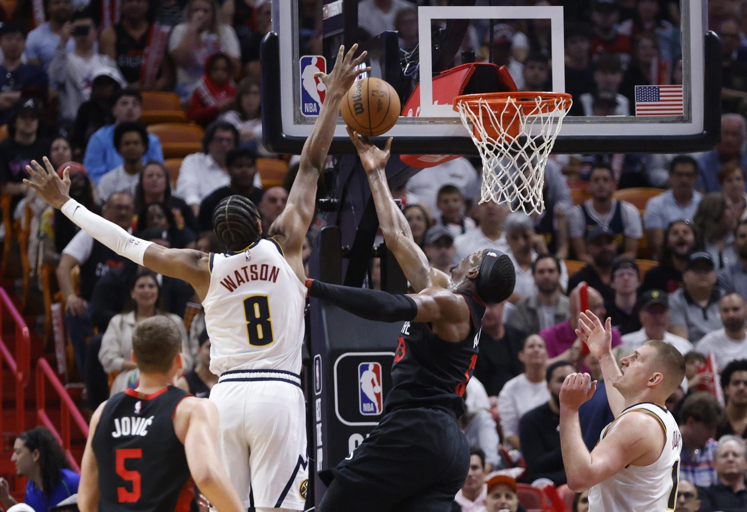 Peyton Watson (2i), alero de los Nuggets de Denver, fue registrado este miércoles, 13 de marzo, al intentar bloquear el ataque Bam Adebayo, ala-pívot de los Heat de Miami, durante un partido de la NBA, en el coliseo Kaseya Center, en Miami (Florida, EE.UU.). EFERhona Wise