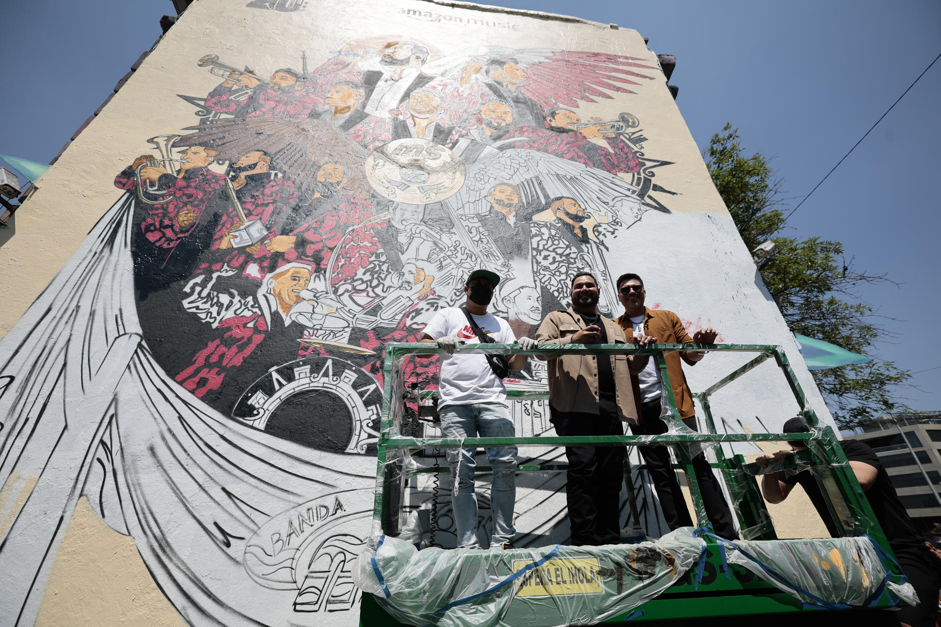 Los integrantes de la Banda MS, Alan Ramírez (c) y Oswaldo Silvas (d) y el artista urbano Andric (i)posan este viernes durante la inauguración de un mural dedicado a la agrupación en Ciudad de México (México). EFE/José Méndez
