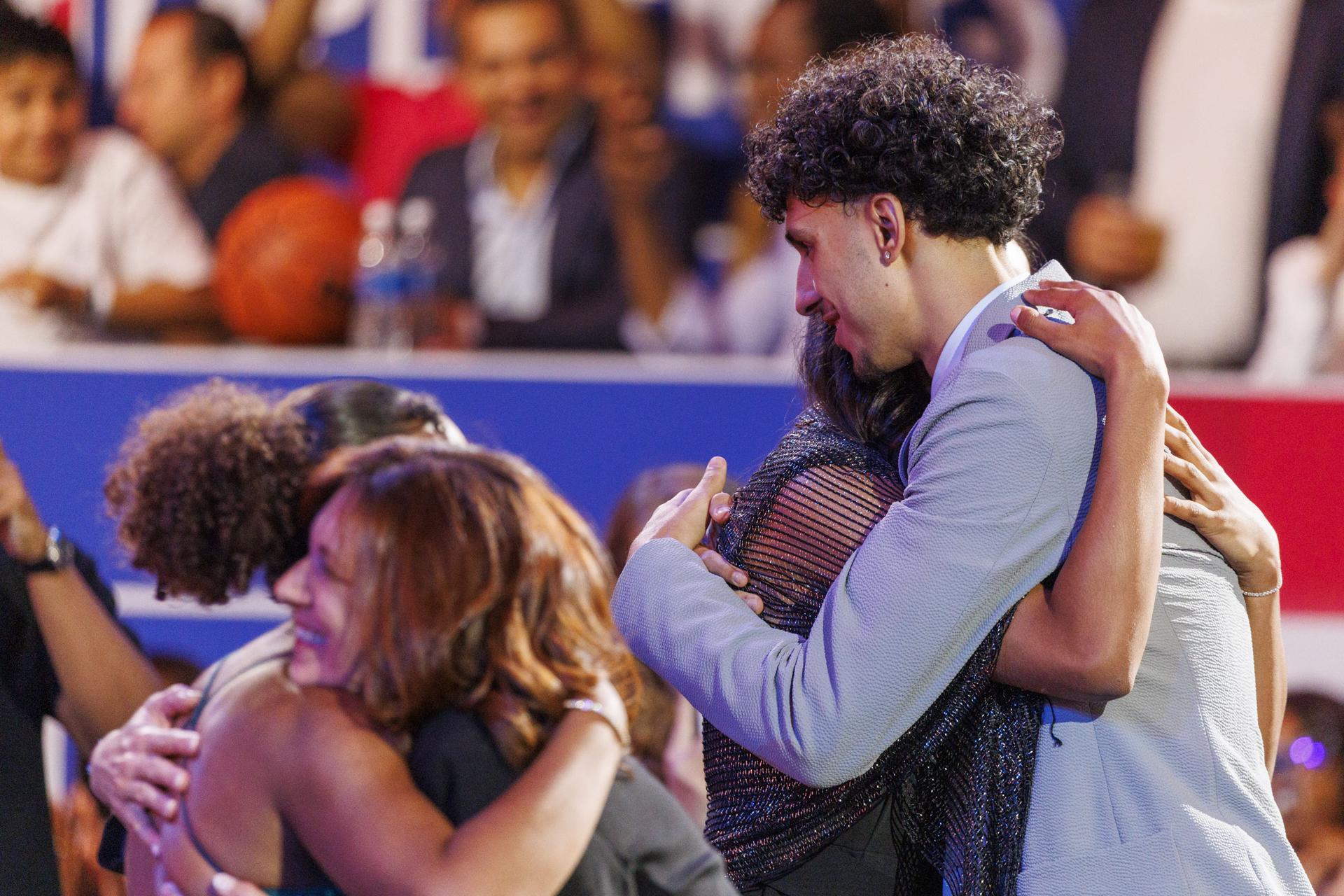 El joven jugador francés de baloncesto y número uno del draft 2024 de la NBA, Zaccharie Risacher (d), fue registrado ese miércoles, 26 de junio, al abrazar a miembros de su familia, después de ser seleccionado por los Atlanta Hawks, en el coliseo Barclays Center de Brooklyn (Nueva York, EE.UU.). EFE/Sarah Yenesel
