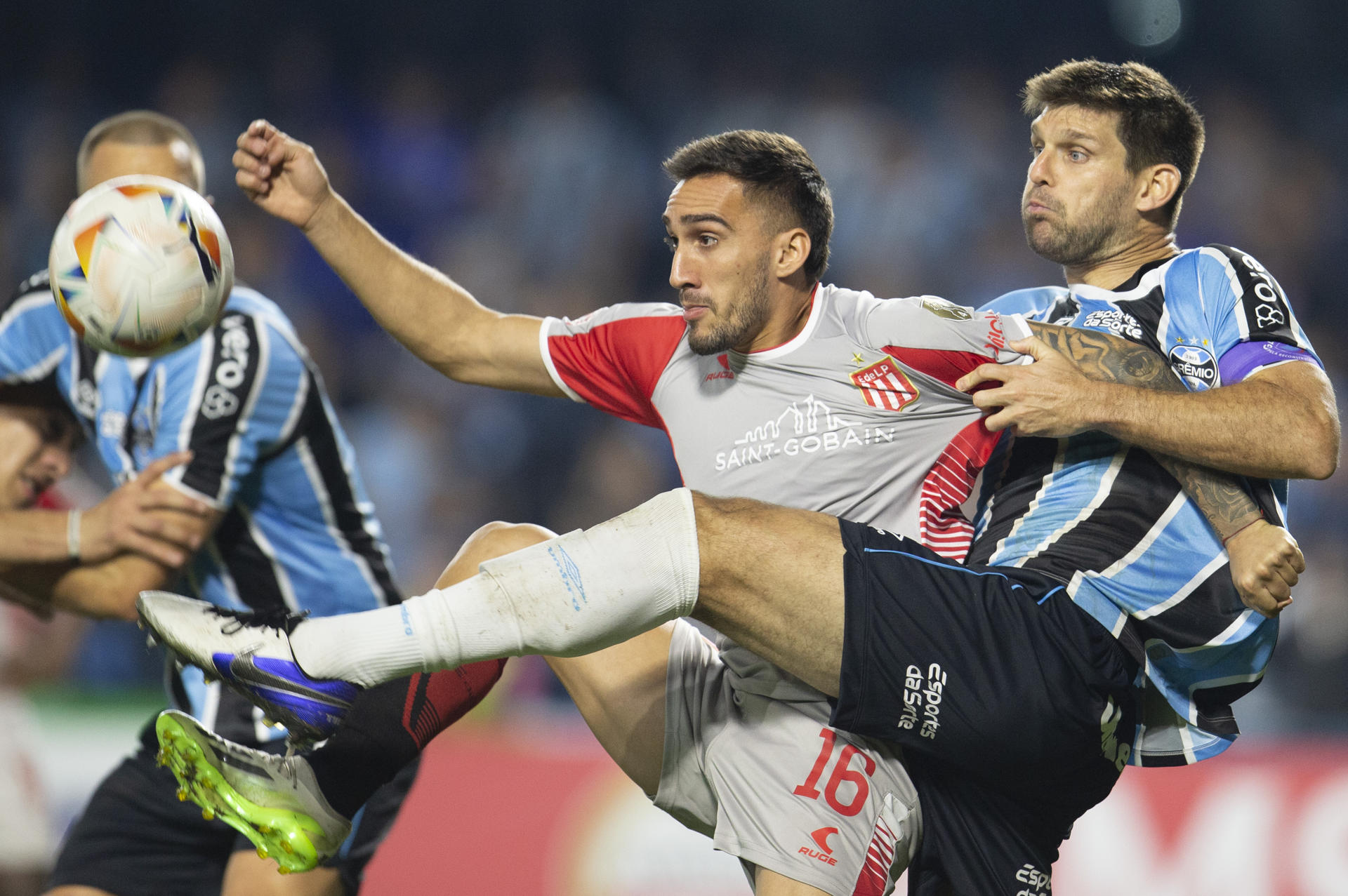 El argentino Walter Kannemann (d), de Gremio, disputa el balón con su compatriota Mauro Acosta, de Estudiantes de La Plata, durante el partido que cerró este sábado la fase de grupos la Copa Libertadores en el estadio Couto Pereira de la ciudad brasileña de Curitiba. EFE/ Hedeson Alves
