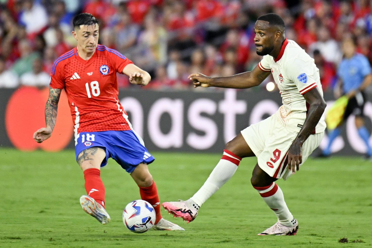 El defensa chileno Rodrigo Echeverría (i) fue registrado este sábado, 29 de junio, al disputar un balón con el atacante canadiense Cyle Larin, durante el partido de cierre del grupo A de la Copa América 2024, en el estadio Inter&Co de Orlando (Florida, EE.UU.). La Conmebol denunció insultos en redes sociales luego de esta partido. EFE/Miguel Rodríguez