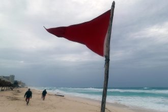 Fotografía de una bandera roja en la playa que indica oleaje agitado y fuertes corrientes, tras la proximidad de la tormenta tropical 'Beryl', el sábado, el balneario de Cancún (México). EFE/Alonso Cupul