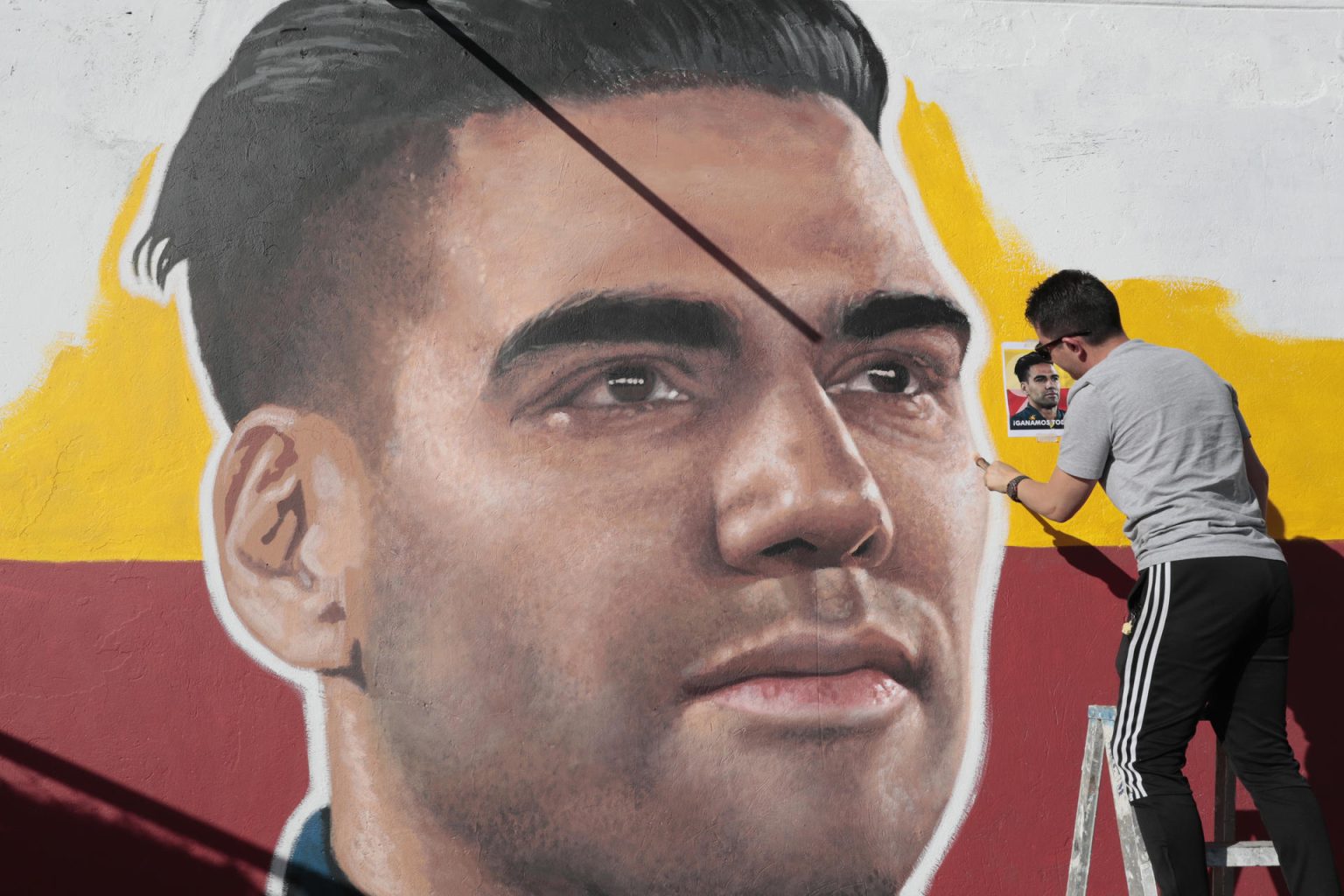 El artista Emerson Cáceres, conocido como Cacerolo, fue registrado este martes, 2 de junio, al pintar un mural con el rostro del futbolista colombiano Radamel Falcao García, en una de las paredes exteriores del estadio Nemesio Camacho ' El Campín', en Bogotá (Colombia). EFE/ Carlos Ortega