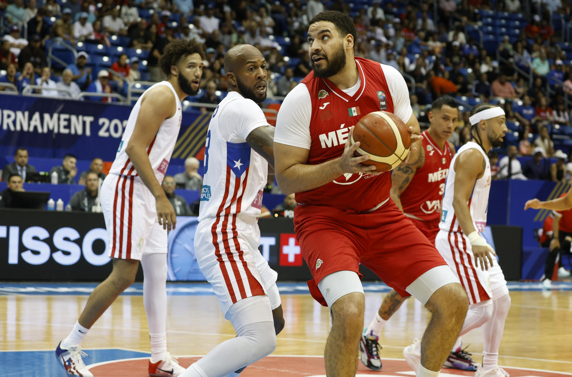 Joshua Ibarra (d) de México hace una entrada ante la defensa de Ismael Romero de Puerto Rico durante un juego de la semifinal del Torneo de Clasificación Olímpica FIBA. EFE/Thais Llorca
