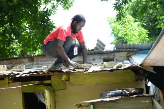 Un hombre protege el techo de su casa con laminas de zinc ante la inminente llegada del huracán Beryl este martes en Saint Thomas (Jamaica). EFE/ Rudolph Brown