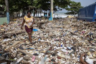 Una mujer camina por la playa Manresa, cubierta de basura tras el paso del huracán Beryl, este miércoles, en Santo Domingo (República Dominicana). EFE/ Orlando Barría