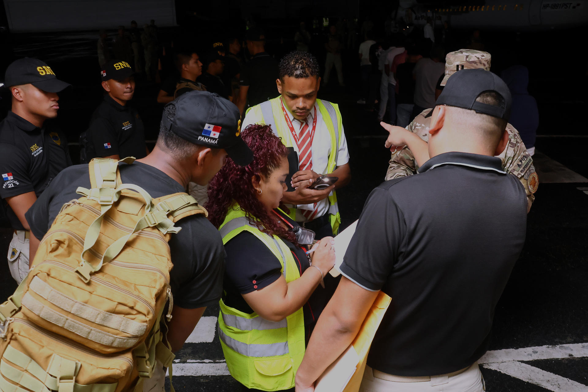 Oficiales de migración de Panamá toman nota de los ciudadanos de nacionalidad ecuatoriana que serán deportados este jueves desde el Aeropuerto Marcos A. Gelabert, en el lado Pacífico del canal de Panamá (Panamá), con destino a la ciudad portuaria de Manta en Ecuador. EFE/Gabriel Rodríguez
