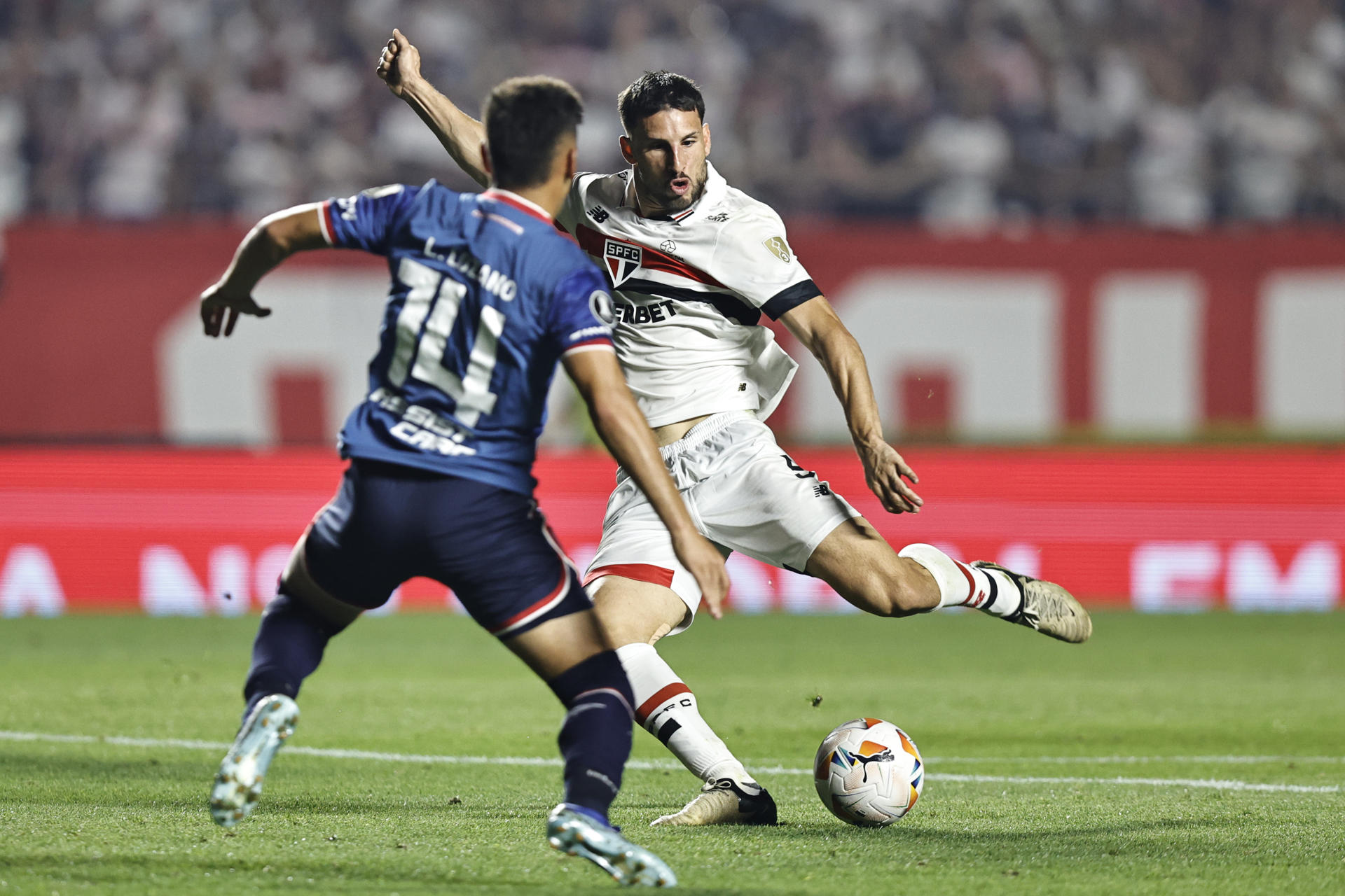 Jonathan Calleri (i), delantero del Sao Paulo de Brasil, fue registrado este jueves, 22 de agosto al intentar patear un balón, ante la marca de Leandro Lozano, durante el partido de vuelta de esta llave de los octavos de final de la Copa Libertadores, en el estadio Morumbí de Sao Paulo (Brasil). EFE/Isaac Fontana
