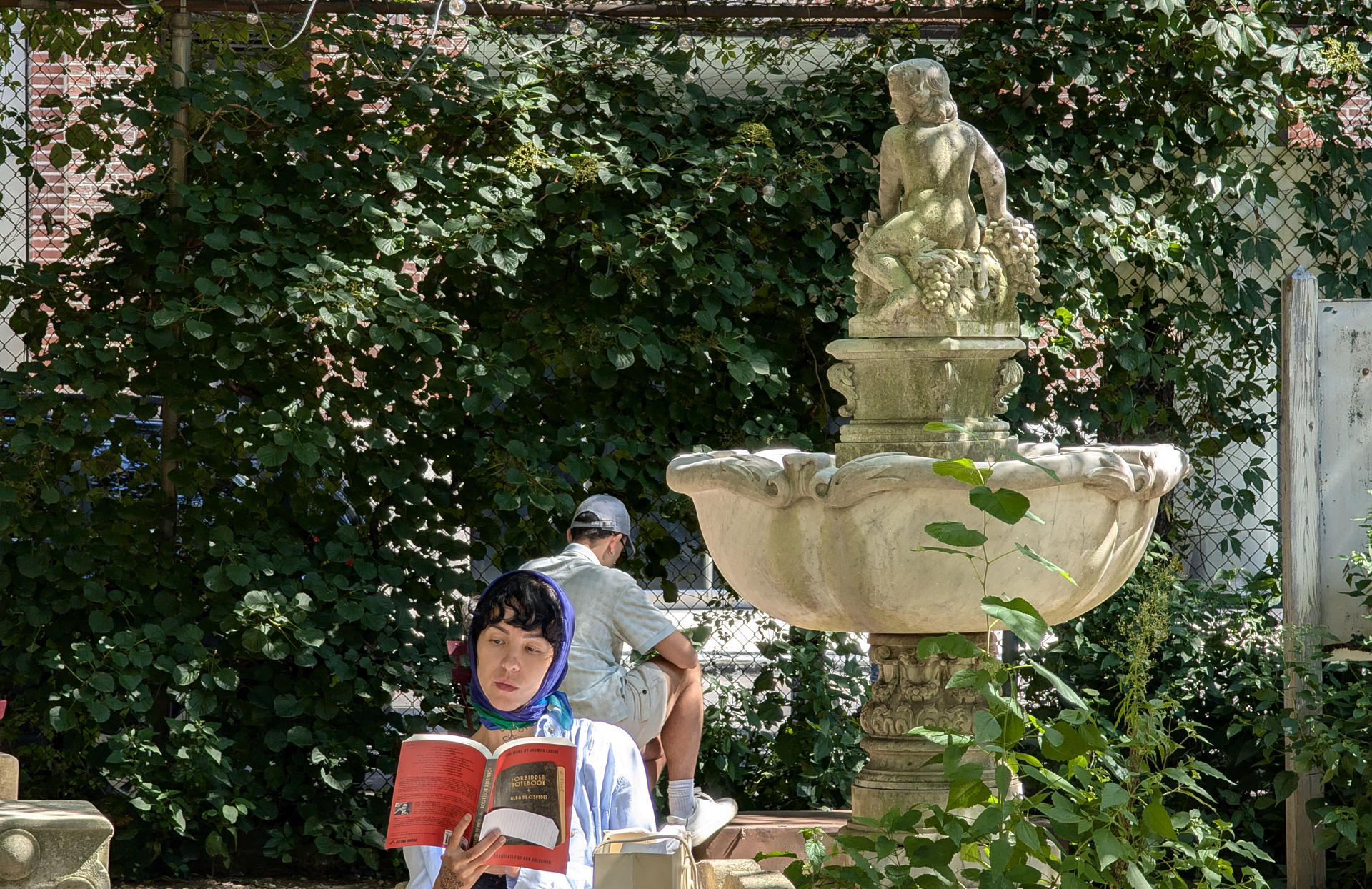 Una persona lee un libro junto a una fuente en el parque Elizabeth Street Garden, el pasado martes en Nueva York (EE.UU.). EFE/Sarah Yáñez-Richards
