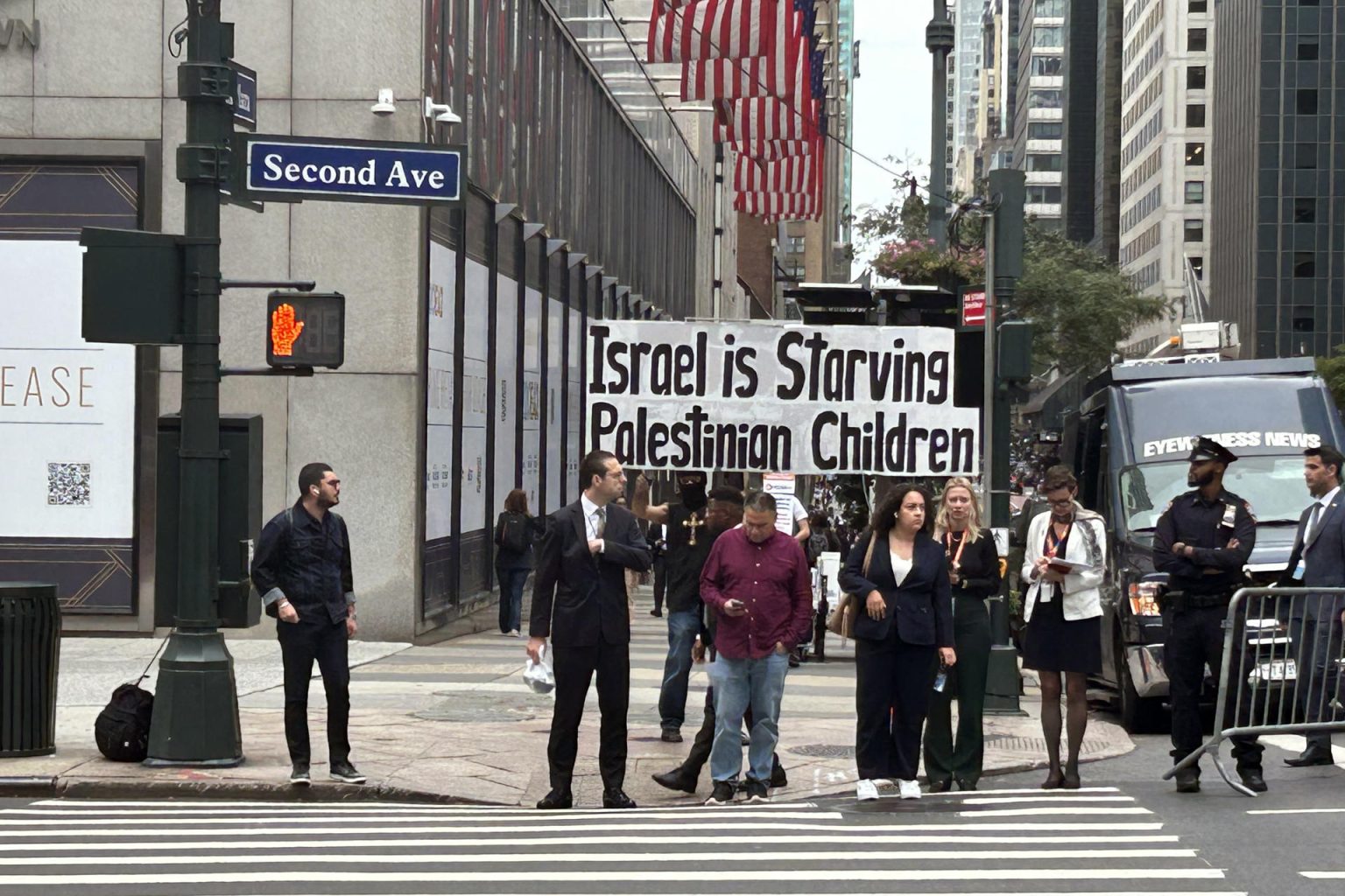 Personas pasan junto a una pancarta que dice 'Israel está matando de hambre a los niños palestinos' este lunes, frente de la sede de las Naciones Unidas en Nueva York (EE.UU.). EFE/ Javier Otazu