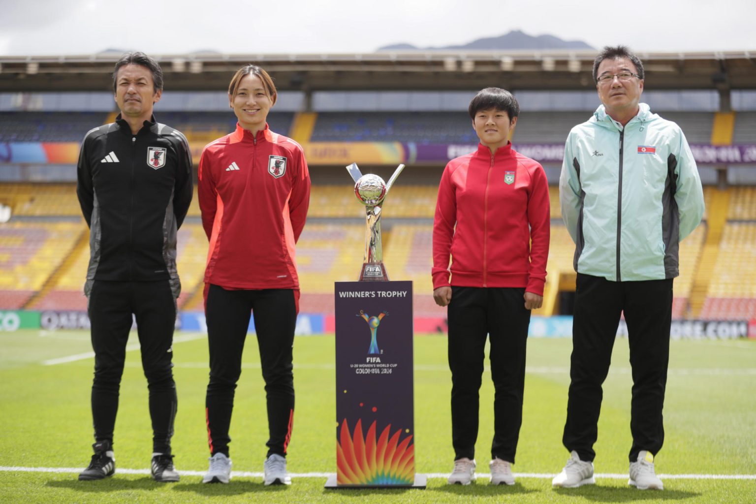 A la izquierda de la copa que recibirá la selección ganadora del Mundial femenino sub-20, el seleccionador de Japón Michihisa Kano y su jugadora Hayashi Manaka. Y del lado derecho la goleadora de Corea del Norte Chae Un Yong y su entrenador Ri Song Ho. Estas selecciones asiáticas disputan el título este domingo en Bogotá. EFE/ Carlos Ortega