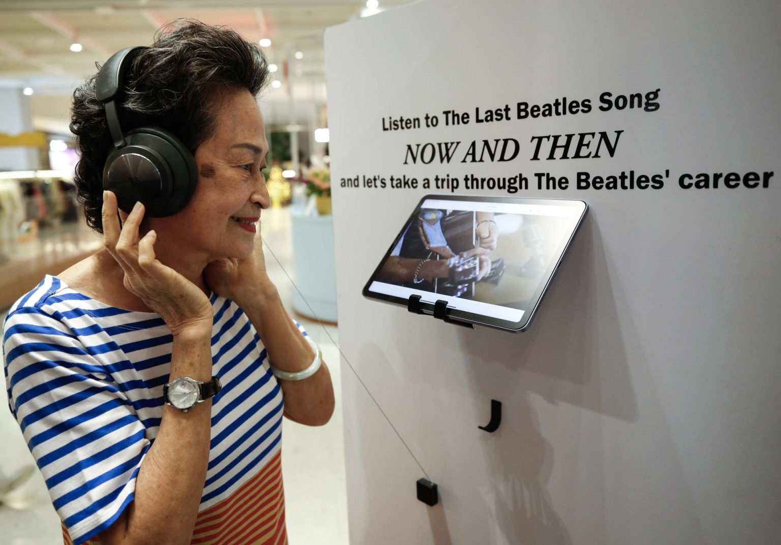 Fotografía de archivo fechada el 23 de noviembre de 2023 de una seguidora de los Beatles escuchando la última canción lanzada de la banda, 'Now And Then', que ha sido creada con la ayuda de inteligencia artificial, durante un evento promocional en Bangkok (Tailandia). EFE/EPA/RUNGROJ YONGRIT/ARCHIVO