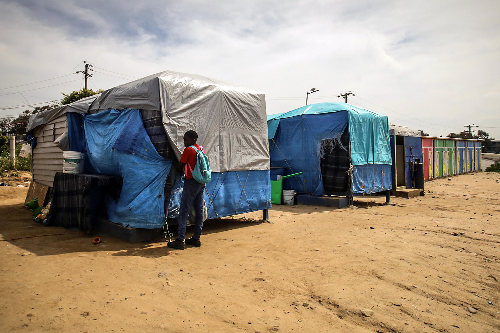 Una persona camina frente una vivienda en la en la Villa Haitiana este domingo en Tijuana (México). EFE/ Joebeth Terríquez
