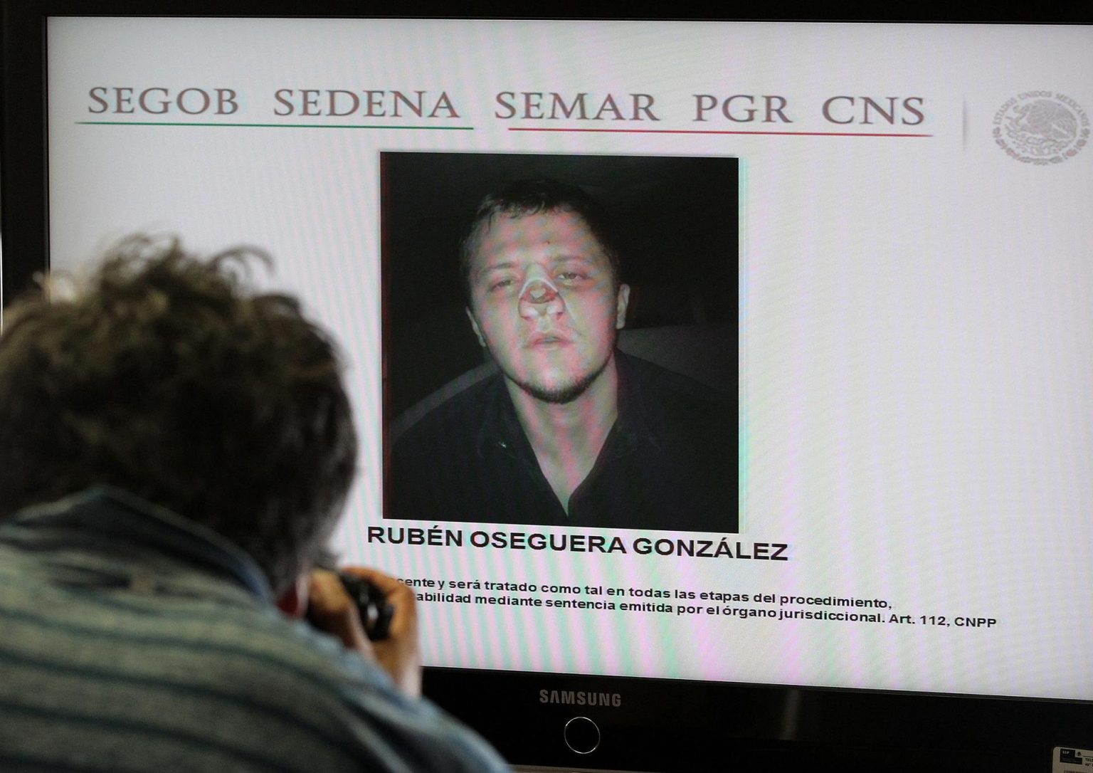 Un fotógrafo toma imágenes a una pantalla con el rostro de Rubén Oseguera González, alias el Menchito durante rueda de prensa en Ciudad de México (México). Imagen de archivo. EFE/Alex Cruz