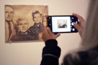 Una persona toma una foto a la obra 'Untitled (Klaus Barbie as a Family)' ('Klaus Barbie en familia'), un rompecabezas con impresión en bolsa de plástico del artista cubano estadounidense Félix González-Torres, durante la presentación de la exhibición 'Felix González-Torres: Always to return' este jueves, en la Galería Nacional de Retratos en el centro de Washington (EE. UU). EFE/Lenin Nolly