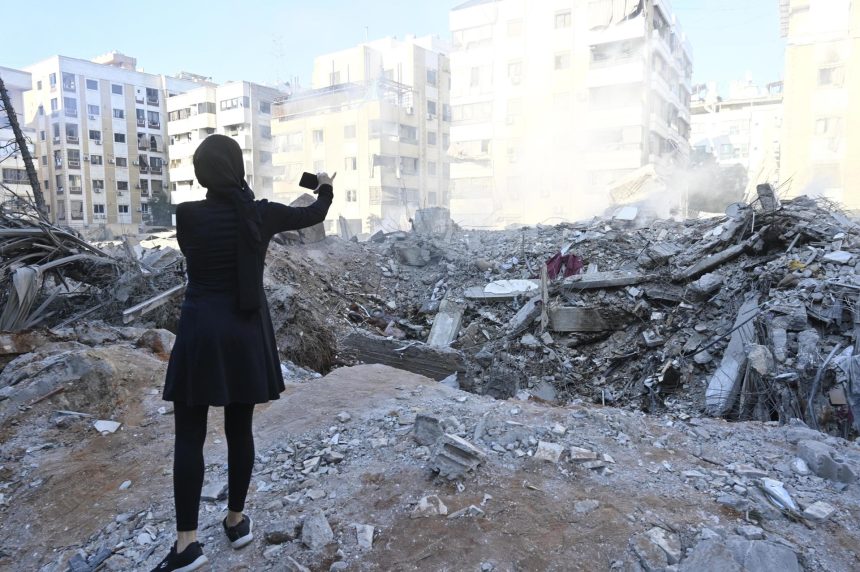 Una mujer toma una foto de un edificio destruido en el barrio de Haret Hreik, en los suburbios del sur de Beirut, tras los ataques militares israelíes sobre Beirut. EFE/ WAEL HAMZEH