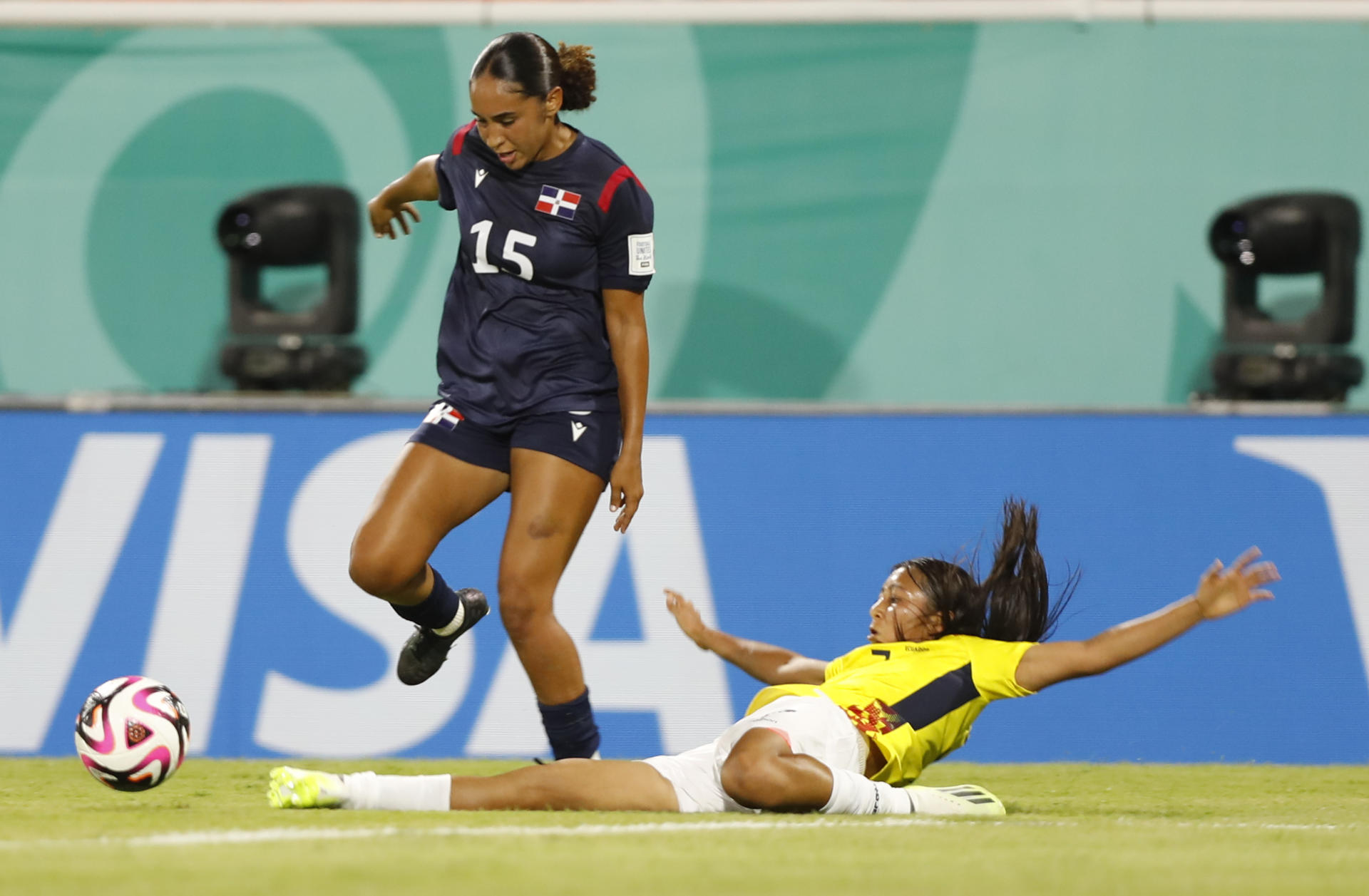 La dominicana Natalie Bruno (i) avanza ante el cierre de la defensora ecuatoriana Evelyn Burgos durante el partido de la primera fecha del Mundial sub-17 que las sudamericanas ganaron por 0-2 en el estadio Cibao de Santiago de los Caballeros. EFE/ Diana Sánchez
