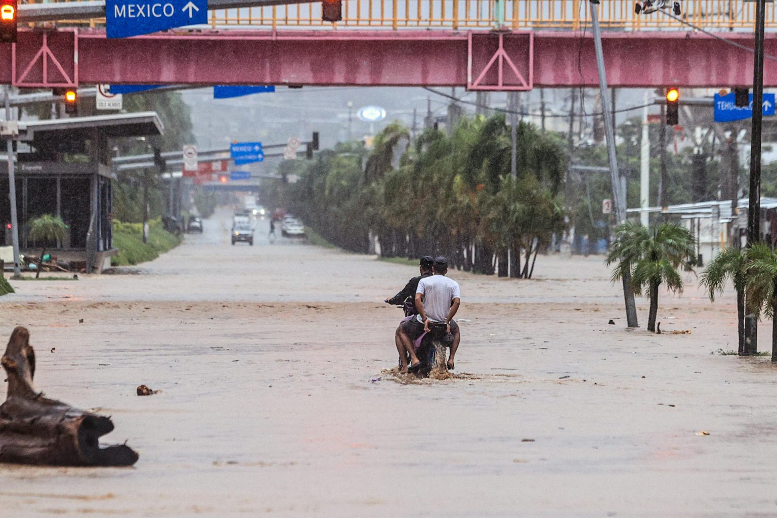 Imagen de archivo de dos personas en una moto que transitan por una calle inundada en Acapulco (México). EFE/ David Guzmán