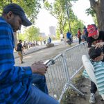 Fotografía que muestra un inmigrante mientras le corta el cabello a otro afuera del refugio de Randall Island en Nueva York (EE.UU.). EFE/Angel Colmenares