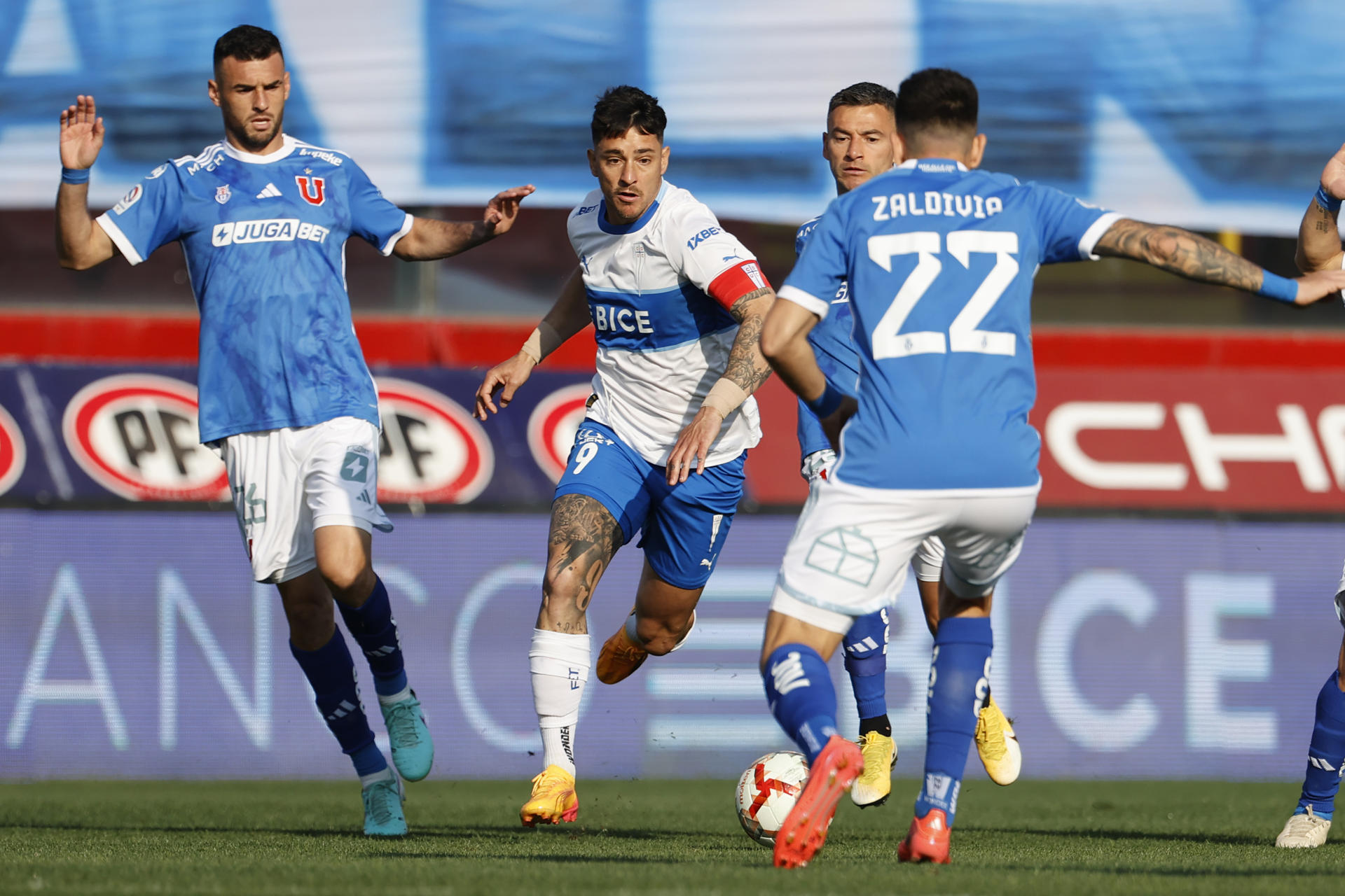 Fernando Zampedri (c) de Universidad Católica, disputa el balón con Matías Zaldivia (d) de Universidad de Chile durante un partido válido por el campeonato nacional chileno de fútbol en el estadio Santa Laura, en Santiago (Chile). EFE/ Elvis González
